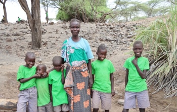 Žena i petero djece stoje i smješkaju se kameri