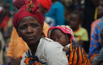 Majka drži dijete koje spava u marami na leđima