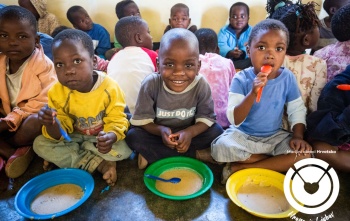 Četiri dječaka sjede na podu i jedu svoj obrok iz tanjura