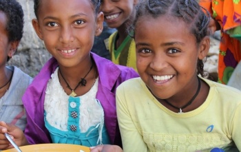 Djevojčice radosno jedu svoju kašu iz tanjura