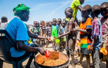 Kuharica dijeli obrok djeci koja čekaju u koloni