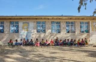 Dječaci sjede uza zid škole i uživaju u svom obroku