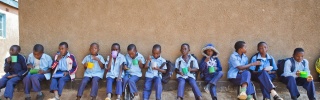 Djeca sjede uz zid u školi dok zajedno jedu.