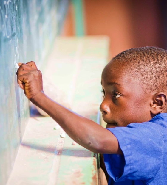Jedan mladi dječak piše na ploči u učionici.