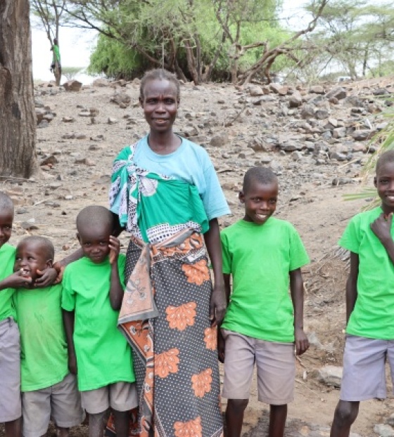 Žena i petero djece stoje i smješkaju se kameri