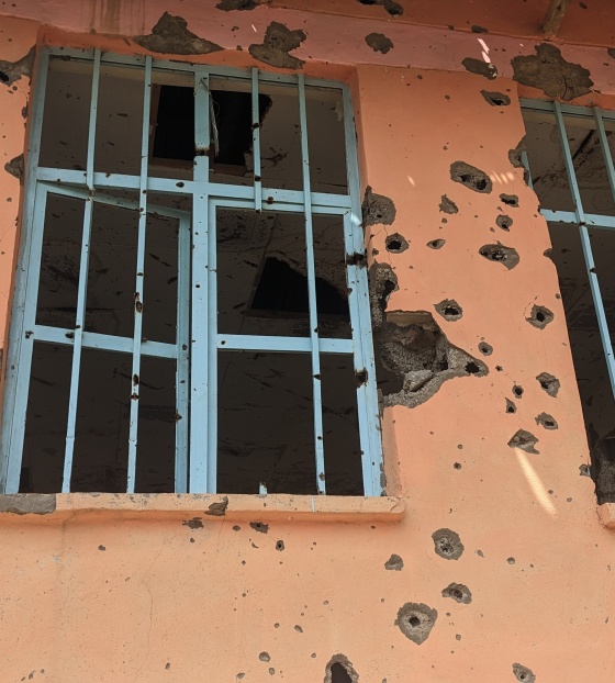 Slika prozora školske zgrade s rupama od gelera.