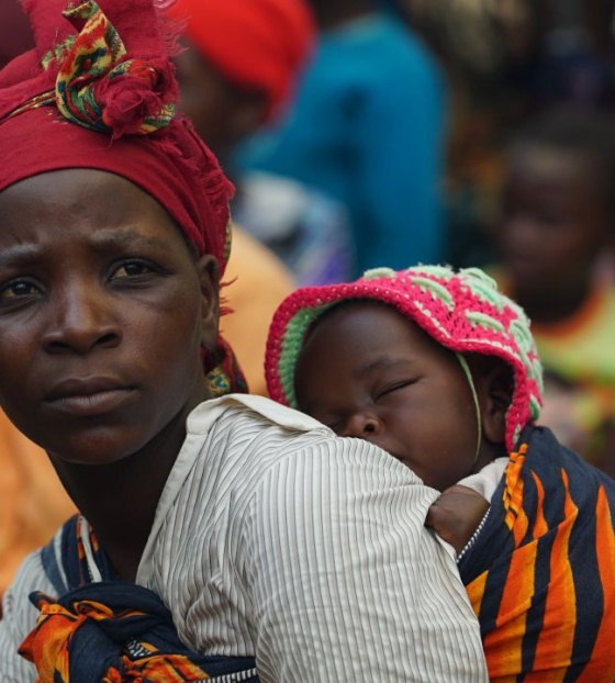 Majka drži dijete koje spava u marami na leđima