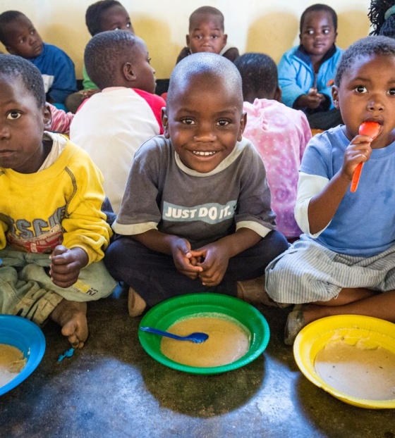 Četiri dječaka sjede na podu i jedu svoj obrok iz tanjura