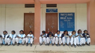 Djeca sjede ispred vrata školske kuhinje