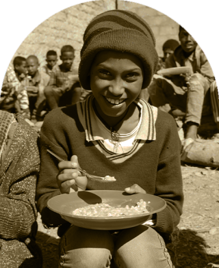 Dijete u Etiopiji sjedi da jede u školi.