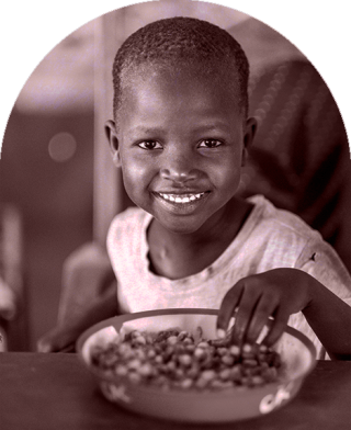 Dijete u Keniji sjedi da jede u školi.